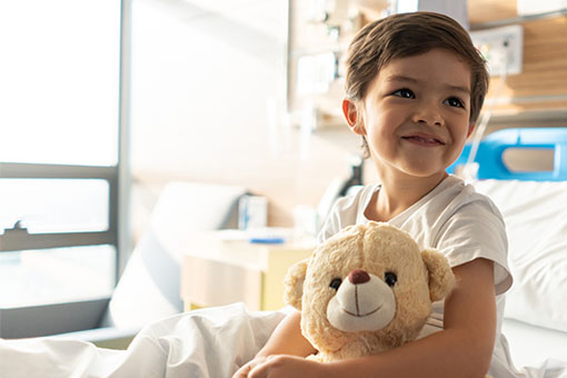 a kid holding a stuffed bear and smiling