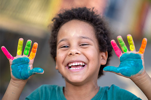a kid with finger paints smiling