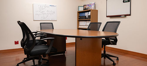 a desk with 2 chairs on one side and one chair on the other