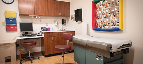 an exam bed with some cabinets and a computer